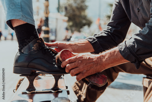 An old man hand polishing and painting a black shoe at street photo