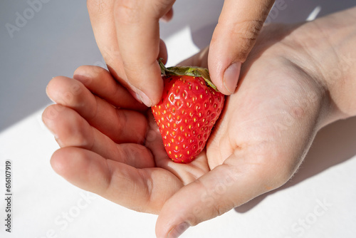 Delicious ripe juicy strawberry berry in a child's palm