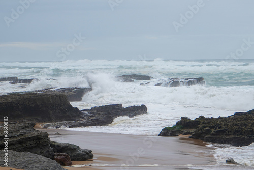 Praia do Magoito, Sintra, Portugal - March 2023: View of the ocean, rocks, sand and waves on the beach. Atlantic Ocean.