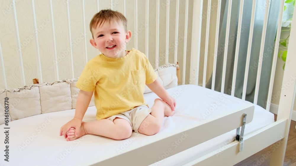 Portrait of a toddler baby sitting in a white crib. Kid aged about two years (one year eleven months)d Portrait of a toddler baby sitting in a white crib. Kid aged about two years (one year eleven months)d