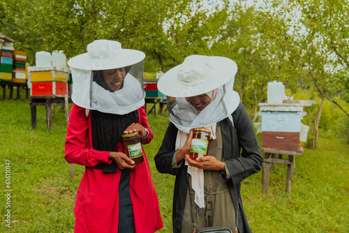 Portrait of an Arab investors holding a jar of honey in their hands while standing in front of a large honey farm. The concept of investing in small businesses