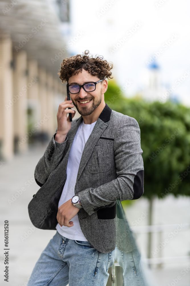 Attractive young businessman using a cell phone in front modern office building on a beautiful sunny day.