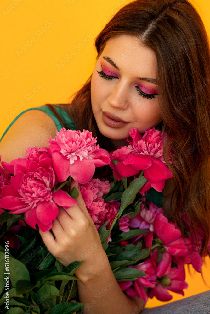 Portrait of a girl with bright makeup and peonies