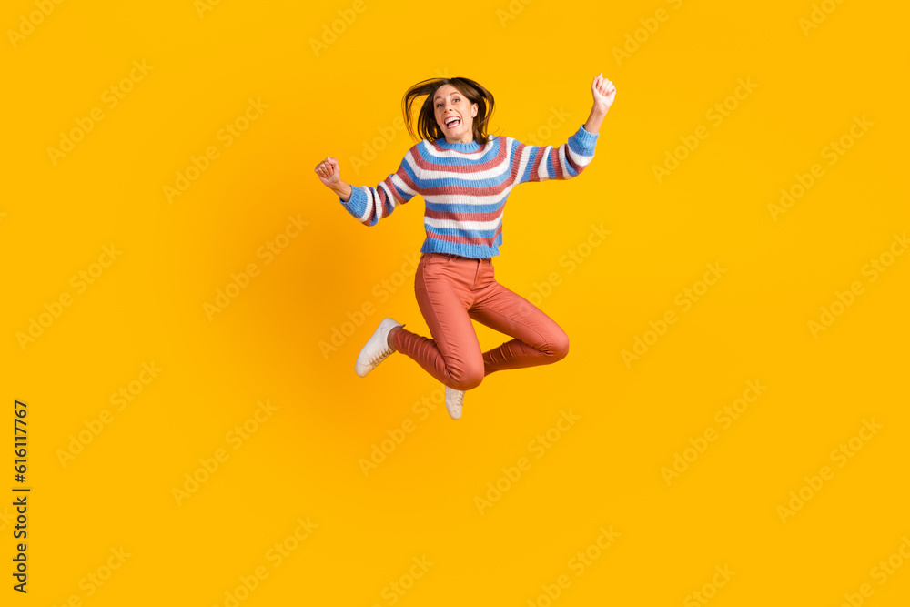 Full body size photo of lovely glad cheerful girl jumping having fun rising hands up isolated on bright vivid shine vibrant color background