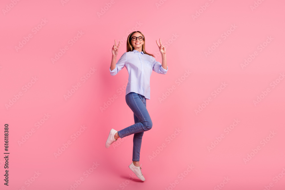 Full length body size photo of girl showing two hands v signs jumping high up isolated pink background Full length body size photo of girl showing two hands v signs jumping high up isolated pink background