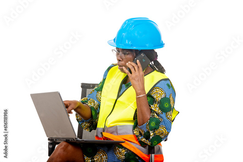 close up of female engineer in protective helmet working using laptop and mobile phone.