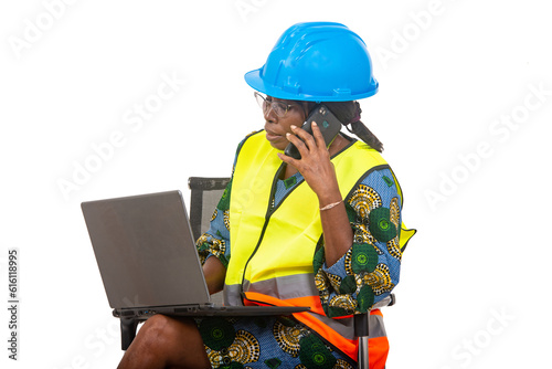 close up of smiling woman engineer in protective helmet working using laptop computer and mobile phone.