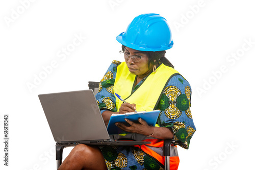 close up of female engineer in protective helmet working using laptop and clipboard, pensive.
