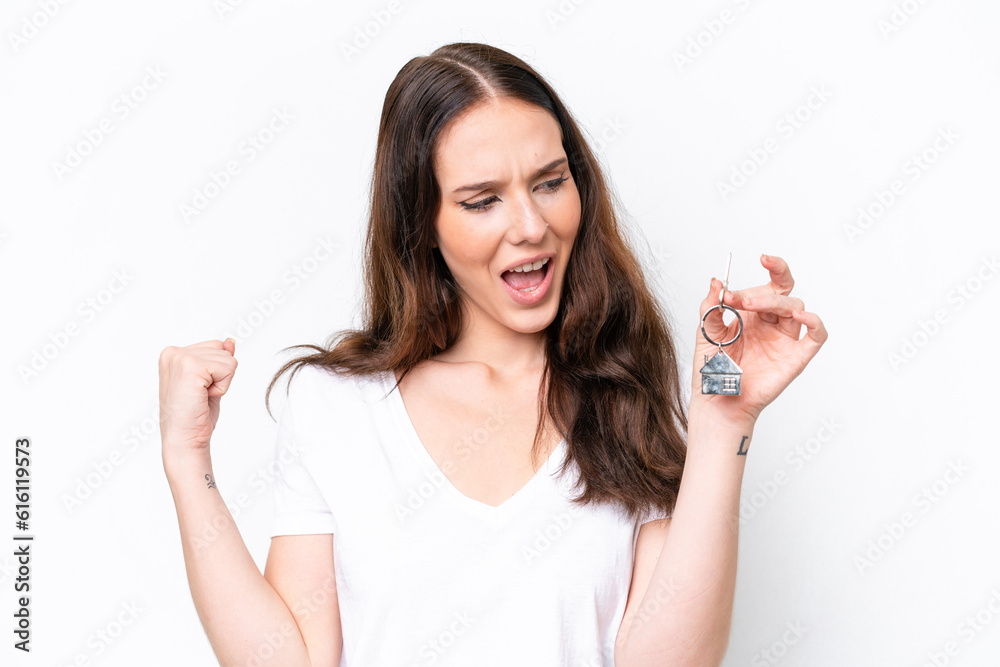 Young caucasian woman holding home keys isolated on white background celebrating a victory Young caucasian woman holding home keys isolated on white background celebrating a victory