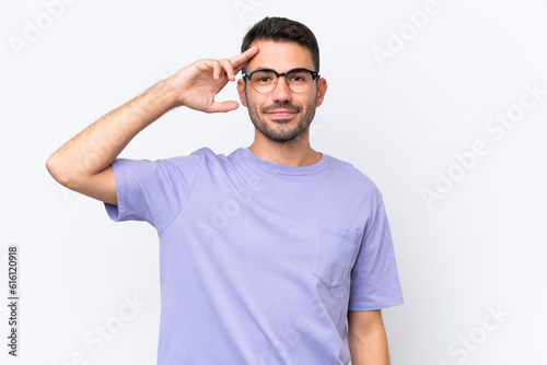 Young caucasian man isolated on white background saluting with hand with happy expression