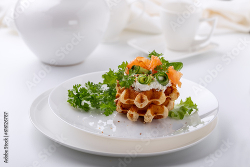 Belgian waffles with red fish and greens on a white dish on a white background