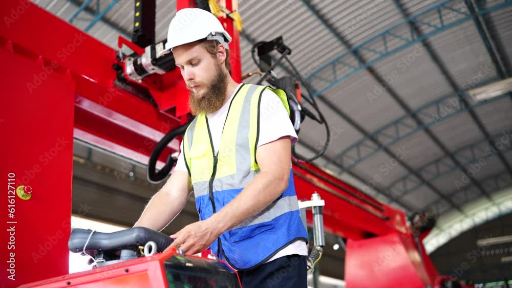 Technician programs a robot arm with a digital tablet and assembly robot in a factory. Apprentice engineers programming robots in factory.