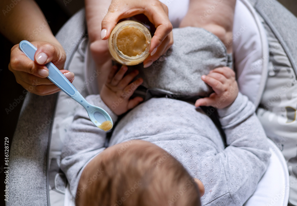 cute adorable boy child eating food from jar mashed puree.mother woman