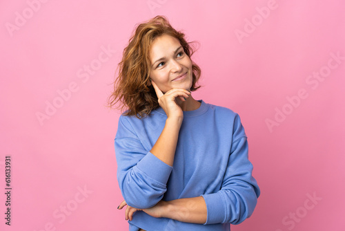 Young Georgian woman isolated on pink background thinking an idea while looking up