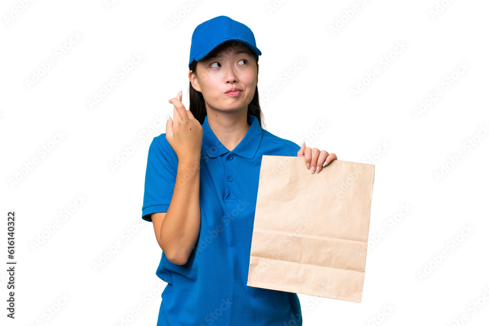 Young Asian woman taking a bag of takeaway food over isolated background with fingers crossing and wishing the best Young Asian woman taking a bag of takeaway food over isolated background with fingers crossing and wishing the best