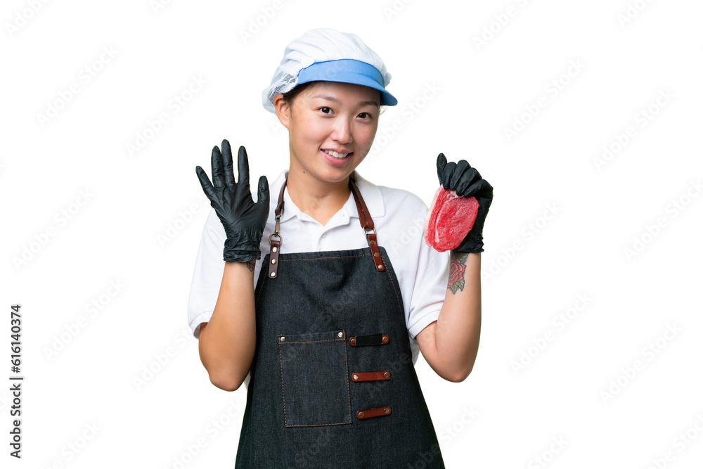 Young caucasian woman wearing an apron and serving fresh cut meat over isolated background saluting with hand with happy expression Young caucasian woman wearing an apron and serving fresh cut meat over isolated background saluting with hand with happy expression
