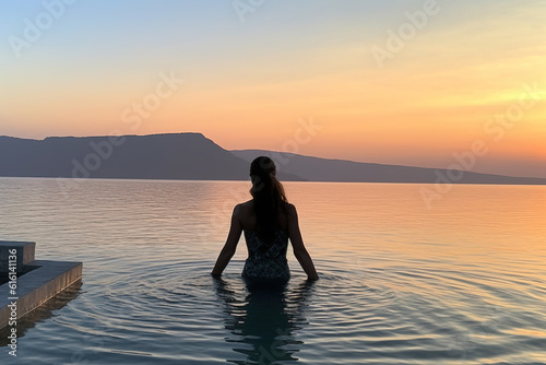 In the background of the sunset at dusk  a girl admires the scenery in the high -end hotel pool © 昊 周