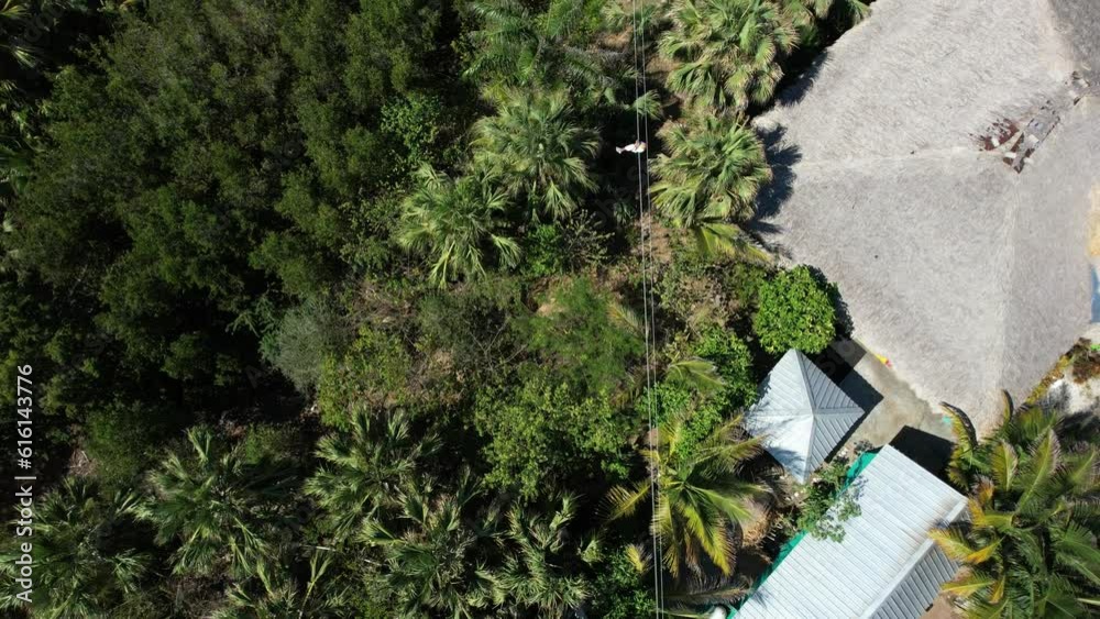 A tourist on a zipline in vertical view on Punta Paitilla beach