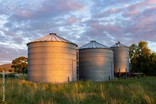 Row of silos on farm at sunset