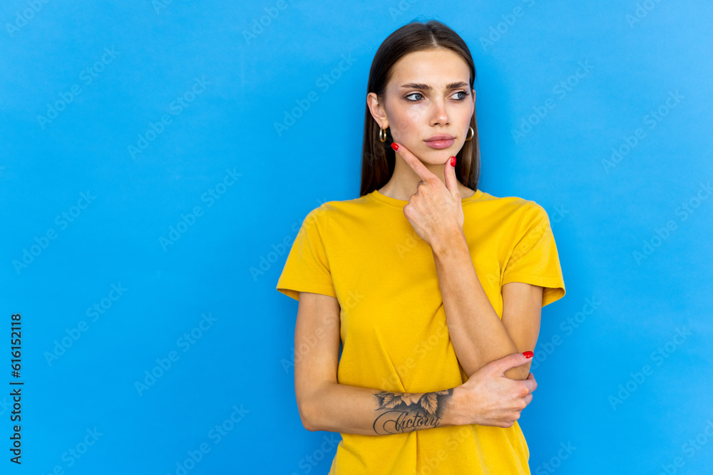 Thinking young lady standing isolated over blue background. Looking aside. Thinking young lady standing isolated over blue background. Looking aside.