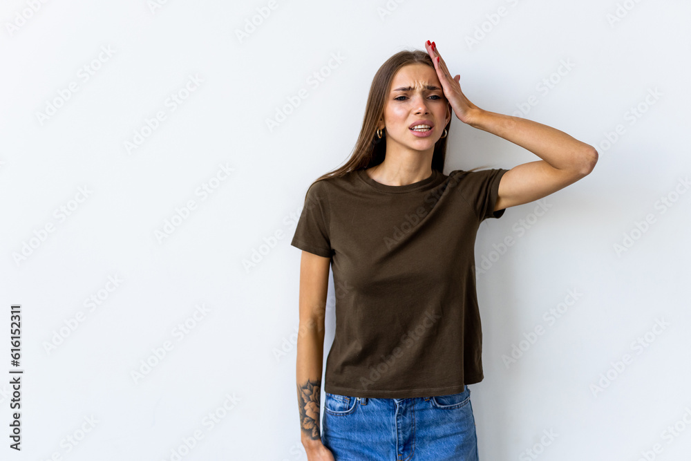 young woman wearing white T-shirt over white background holding hand on head with frightened and regret expression. young woman wearing white T-shirt over white background holding hand on head with frightened and regret expression.