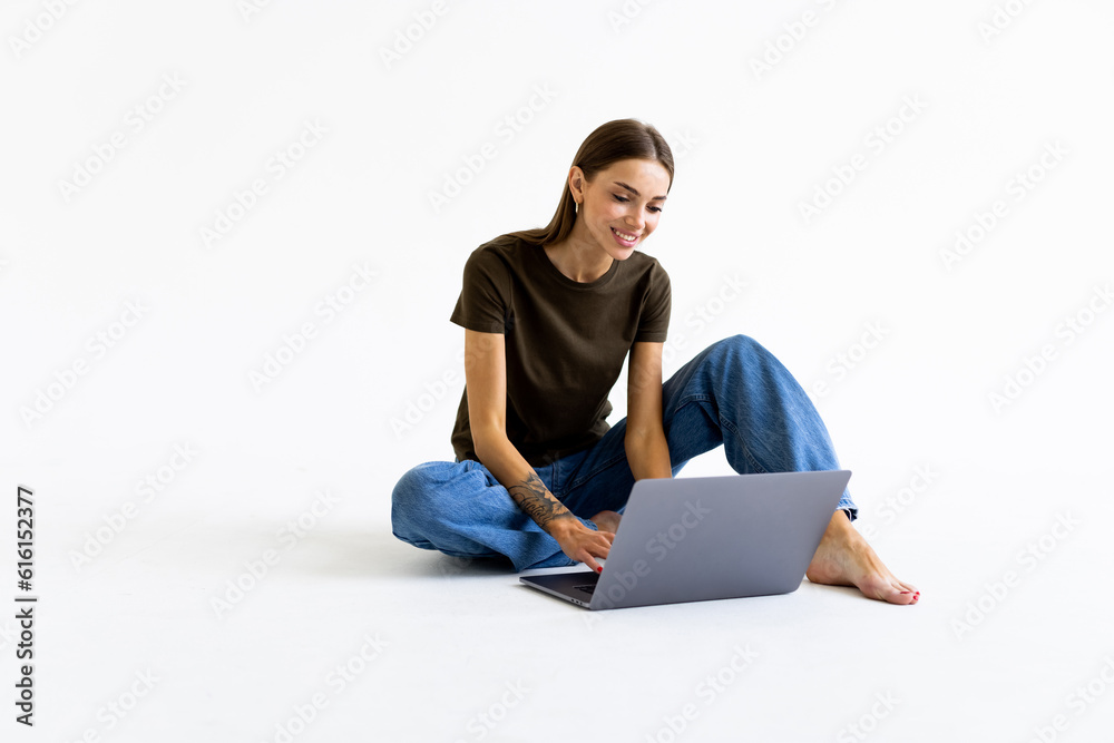 Young woman sitting on the floor and using laptop on white background Young woman sitting on the floor and using laptop on white background