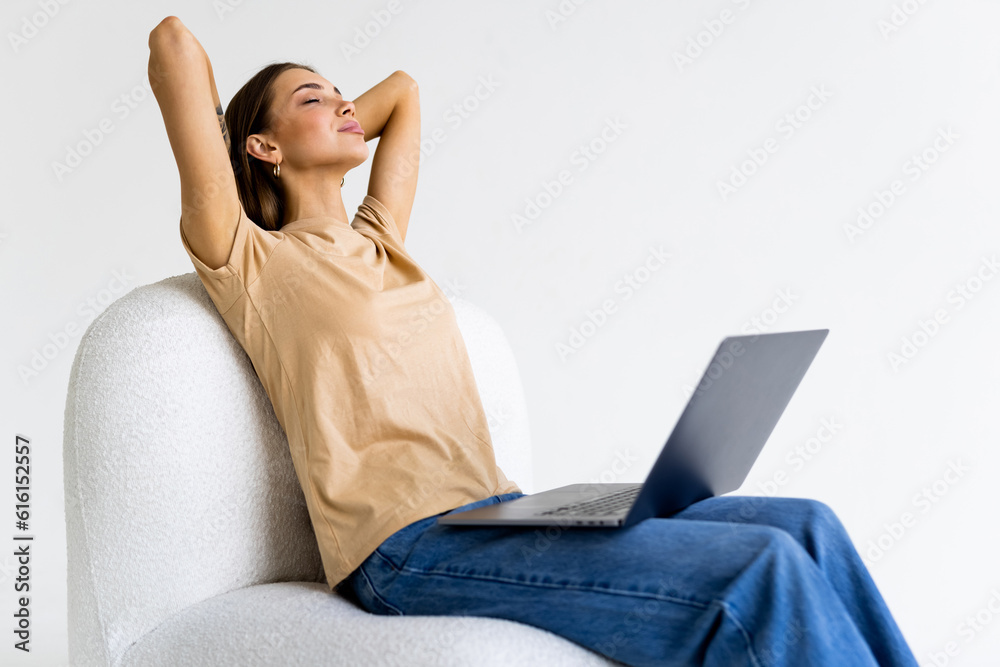 Naklejka premium Young woman sitting in bag chair using laptop isolated over white background