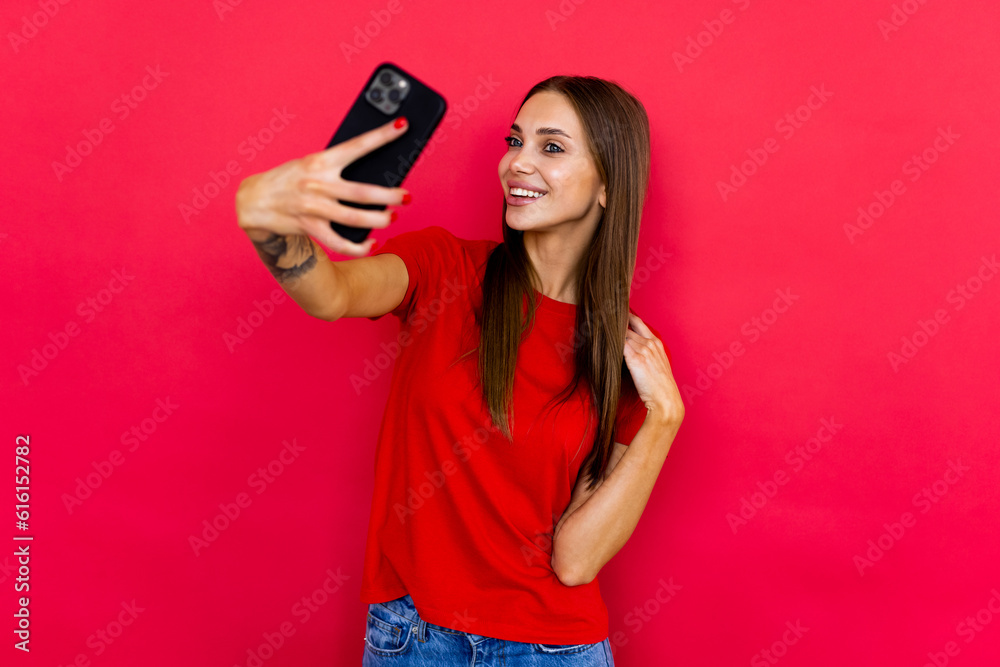 Handsome young woman is taking a selfie on phone over red background. Handsome young woman is taking a selfie on phone over red background.