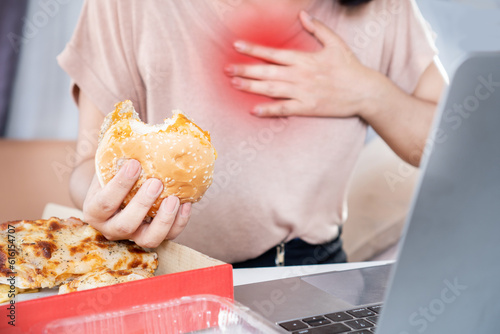 woman suffering from acid reflux , heartburn after over eating junk food, pizza and burger photo