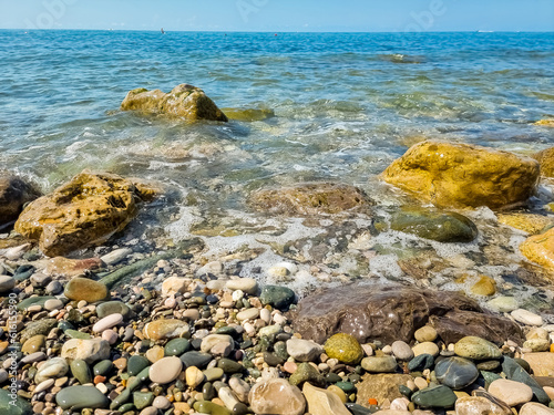 Stones on beach and sea water.Waves in sea near coastline on empty pebble beach. Coast pebbles. Shore landscape on Europe resort. Ocean shoreline scenic.