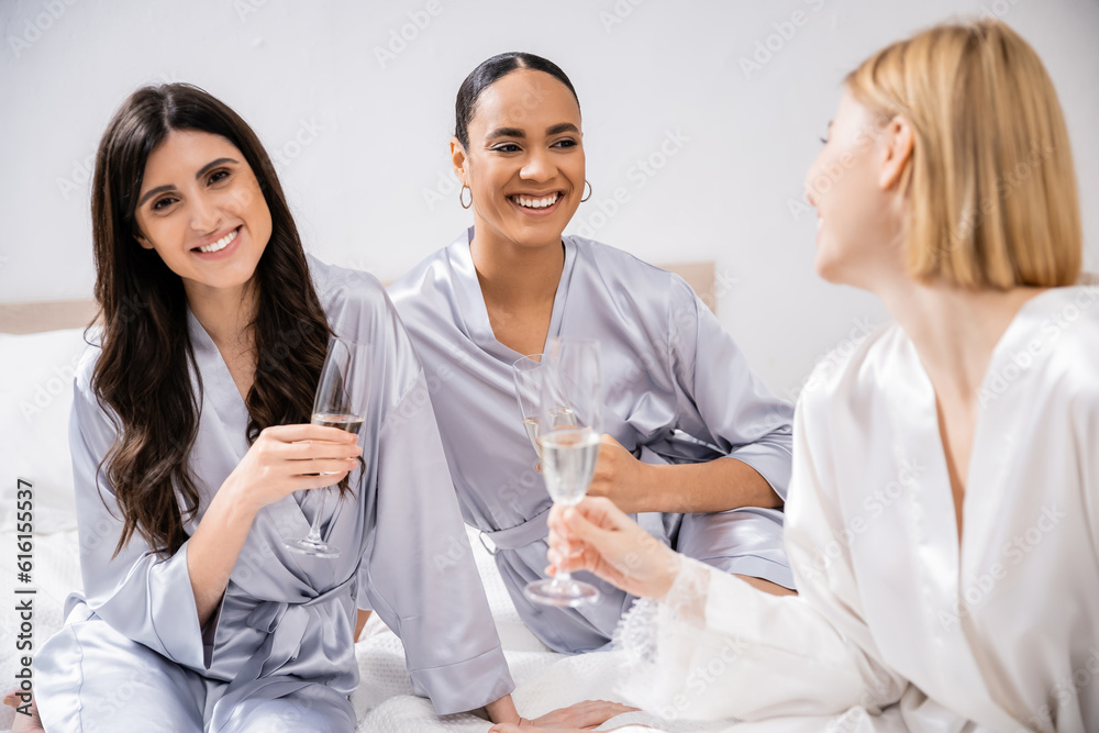 bridal party, wedding prep, interracial girlfriends holding glasses with champagne, celebration, brunette and blonde women, bride and her bridesmaids, cultural diversity, excitement, bedroom bridal party, wedding prep, interracial girlfriends holding glasses with champagne, celebration, brunette and blonde women, bride and her bridesmaids, cultural diversity, excitement, bedroom