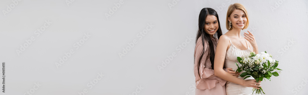 special occasion, asian bridesmaid hugging beautiful bride, friendship goals, grey background, happy girlfriends, bridal bouquet, blonde and brunette women, white flowers, positivity, banner special occasion, asian bridesmaid hugging beautiful bride, friendship goals, grey background, happy girlfriends, bridal bouquet, blonde and brunette women, white flowers, positivity, banner