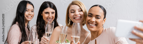four women, beautiful bride and her interracial bridesmaids taking selfie together, happiness, champagne glasses, bridal bouquet, wedding dress, bridesmaid gown, brunette and blonde women, banner