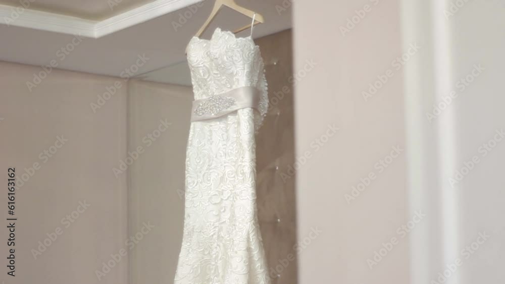 Beautiful expensive wedding dress in bedroom hanging on hanger Beautiful expensive wedding dress in bedroom hanging on hanger
