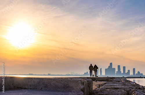 Photography A couple walking along the lakeshore in Ontario Place at sunset, with the Humber