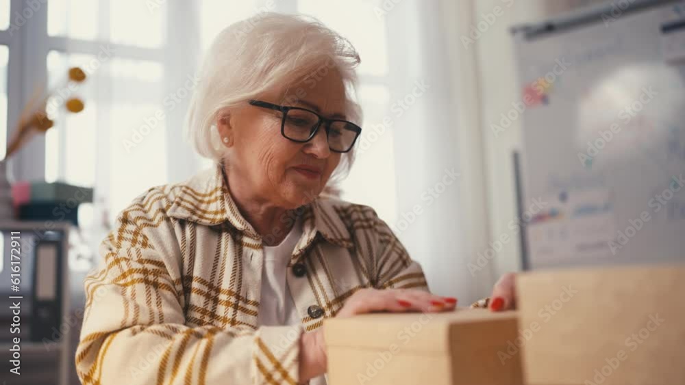 Mature woman packing orders in boxes, female entrepreneur, small business owner Mature woman packing orders in boxes, female entrepreneur, small business owner