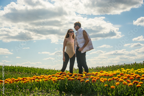 Obraz na płótnie A beautiful young couple, fashion models stands in sportswear at the background of a field of colorful tulips. w salonie