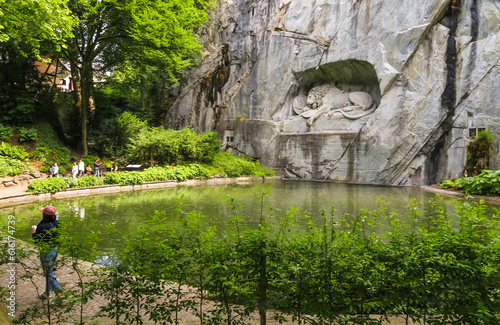 Beautiful view of Lucerne's famous lion monument carved in stone, nestled in a rocky grotto in a charming park where visitors can admire this mournful and moving masterpiece of stone. photo