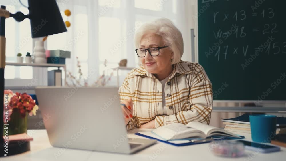 Smiling senior woman teacher teaching lesson online using laptop, e-learning Smiling senior woman teacher teaching lesson online using laptop, e-learning