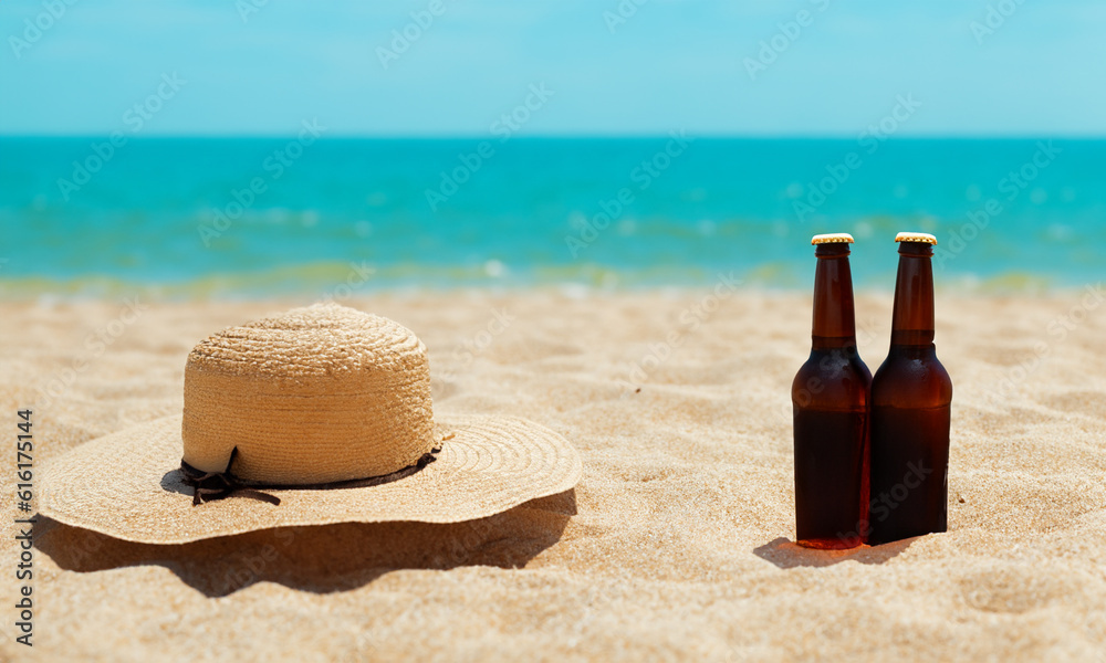 Hat and a beer bottles on the beach. Closeup on the sand in the foreground with blurred sea in the background. Hat and a beer bottles on the beach. Closeup on the sand in the foreground with blurred sea in the background.