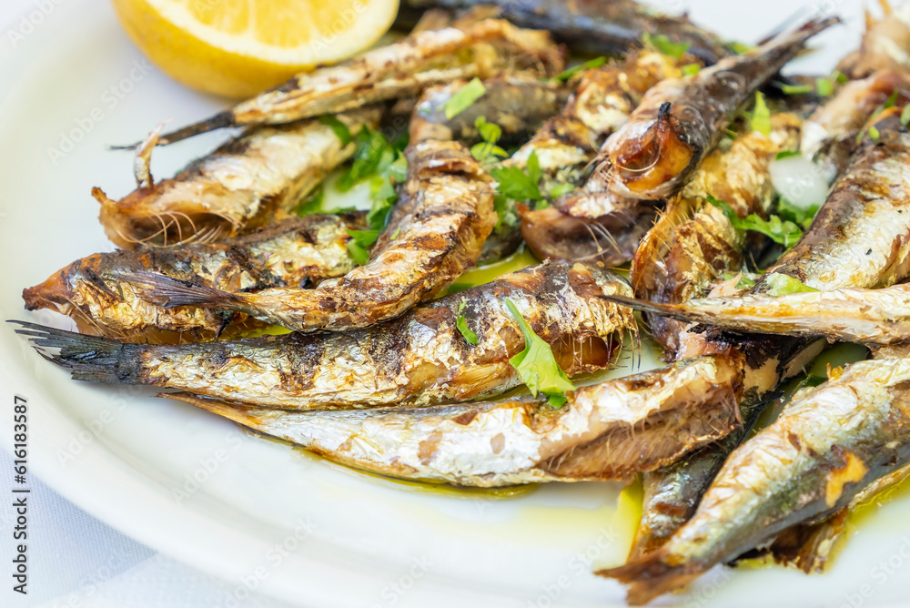 Plateful of Grilled Sardines Served with a Slice of Lemon in a Restaurant in Greece Plateful of Grilled Sardines Served with a Slice of Lemon in a Restaurant in Greece