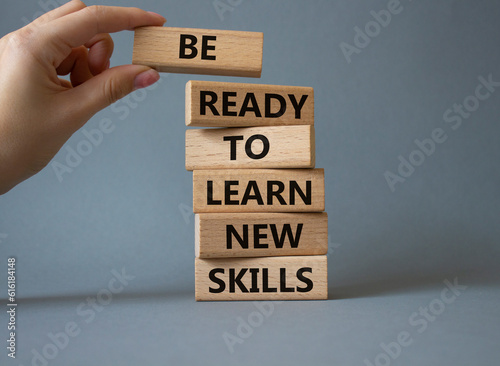 Learn new skills symbol. Concept words Be ready to Learn new skills on wooden blocks. Beautiful yellow background. Businessman hand. Business and Learn new skills concept. Copy space.
