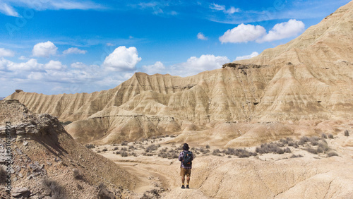 Panoramic view of the colored stone desert and traveler on his back walking on the rocks
