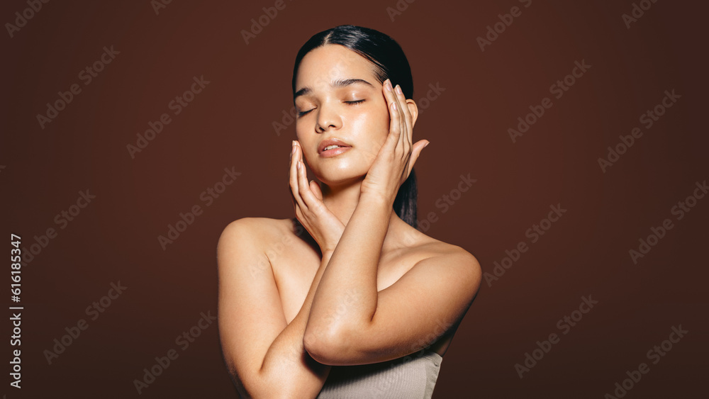 Obraz premium Beautiful young woman touches her flawless skin in a studio