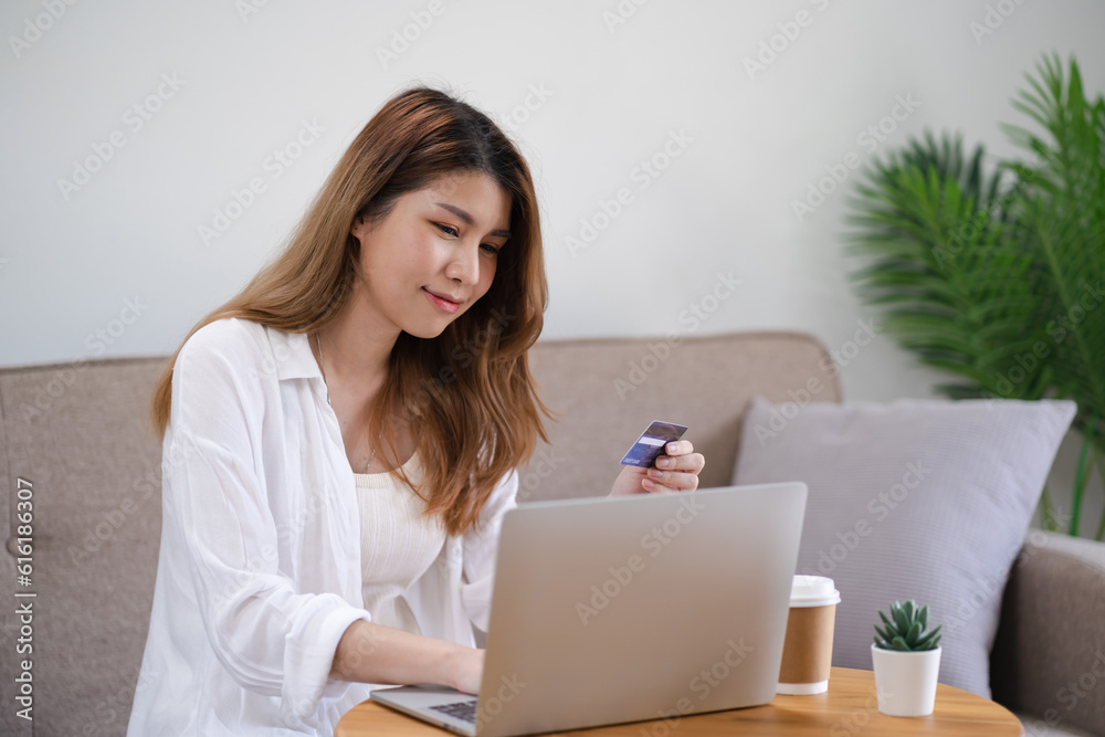 Woman shopping on laptop holding credit card for Internet online e-commerce shopping spending money Online shopping Mobile phone laptop technology concept Woman shopping on laptop holding credit card for Internet online e-commerce shopping spending money Online shopping Mobile phone laptop technology concept