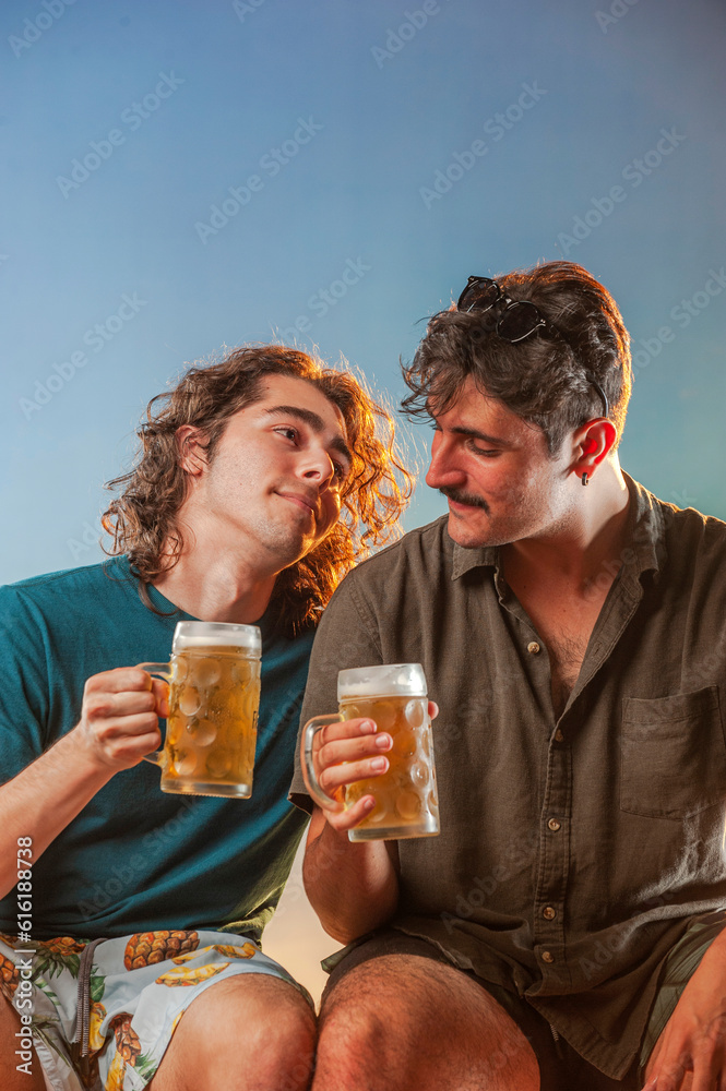 Couple of men toasting draft beer against the sunset.