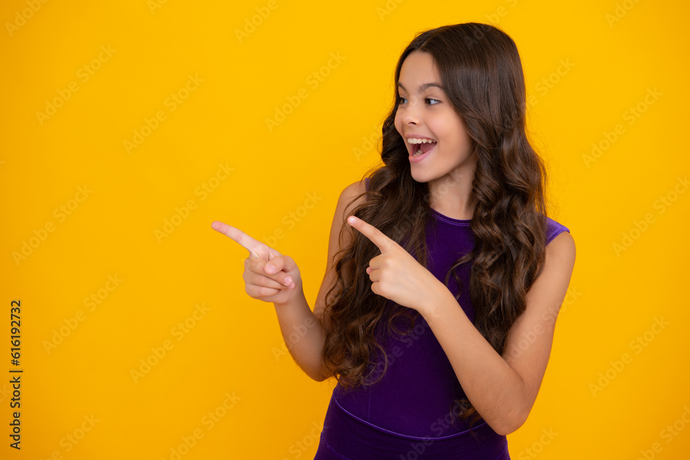 Happy girl face, positive and smiling emotions. Look at advert. Teenager child points aside shows blank copy space for text promo idea presentation, poses against yellow background. Happy girl face, positive and smiling emotions. Look at advert. Teenager child points aside shows blank copy space for text promo idea presentation, poses against yellow background.
