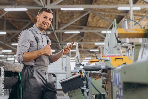 Factory male bearded worker is programming a CNC milling machine with copy space.