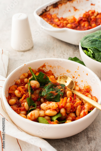 Healthy breakfasts and lunches, stewed white beans with carrots, onions and tomatoes with spinach leaves, a bowl of beans and spinach