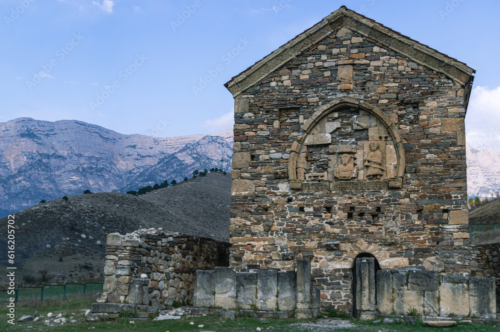 An ancient stone temple high in the mountains. Place of religious ceremonies. The old church on the background of the mountains. History and memory immortalized in stone.